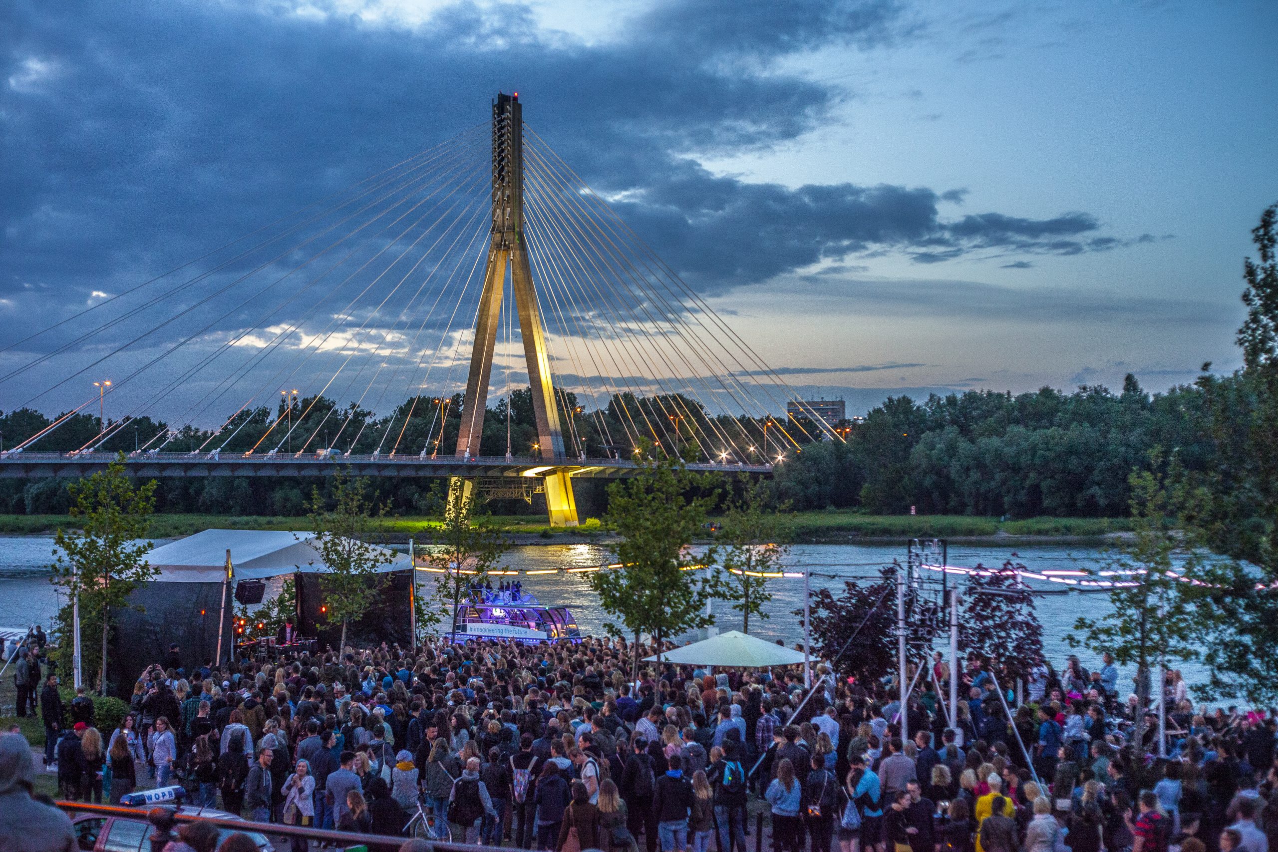 Koncert w lokalu Plac Zabaw nad Wisłą - wieczór, tłum ludzi, w tle Wisła i most Świętokrzyski
