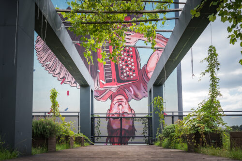 Pergola, rośliny, mural z akordeonistą.