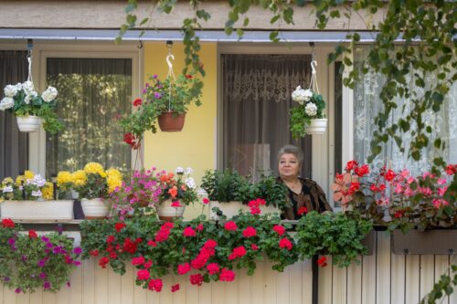 Balkon cały w kwiatach i kobieta.