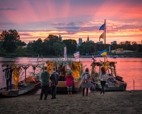 Ludzie czekają na plaży na rejs kolorowymi barkami po Wiśle