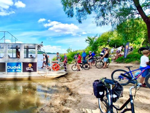 Rowerzyści wchodzą na prom na plaży nad Wisłą