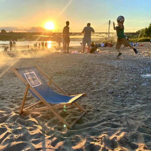 Ludzie odpoczywają na plaży Poniatówka. Chłopiec bawi się piłką