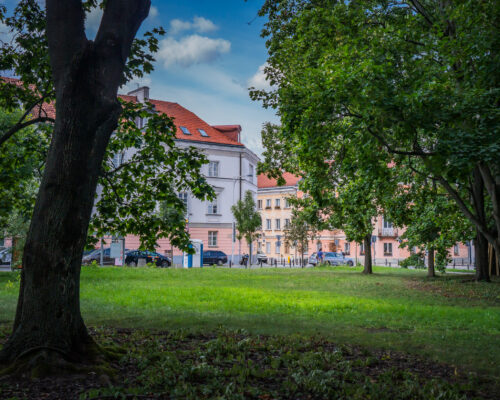 Skwer Radiowej Rodziny Matysiaków - trawa, drzewa, zabytkowe domy w tle