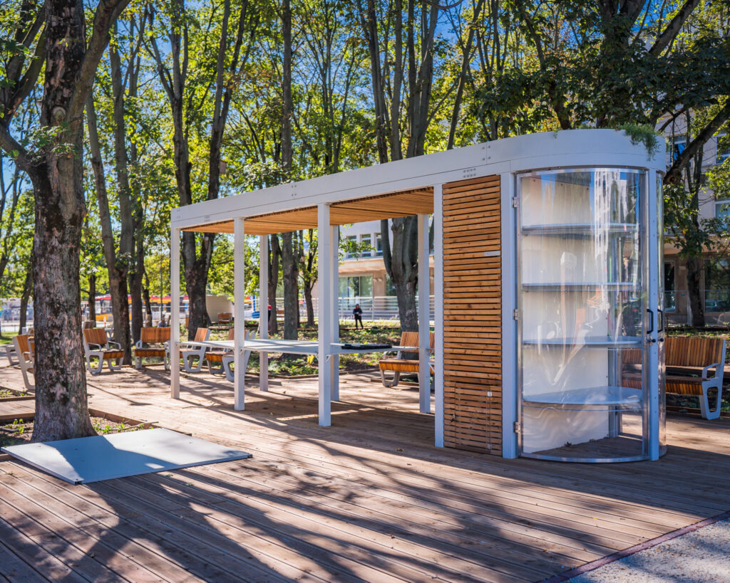 drezwniano-stalowy kiosk na tle drzew