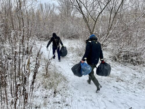 Osoby niosą śmieci w workach nad Wisłą
