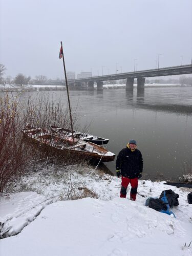 Mężczyzna na tle drewnianej łodzi nad Wisłą