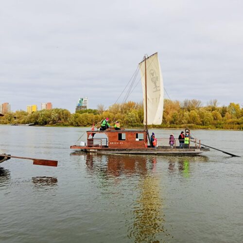 Osoby płyną drewnianą łodzią