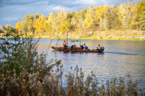 Osoby płyną drewnianą łodzią na Wiśle, jesień