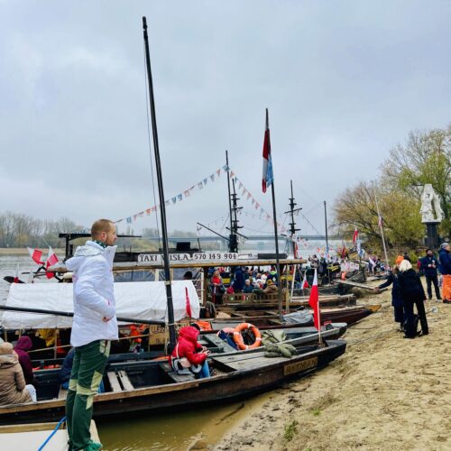 Drewniane łodzie nad Wisłą, ludzie czekają na rejs