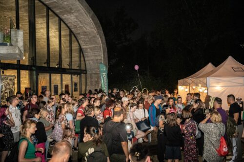 Tłum ludzi w nocy przed Pawilonem Edukacyjnym Kamień, namioty