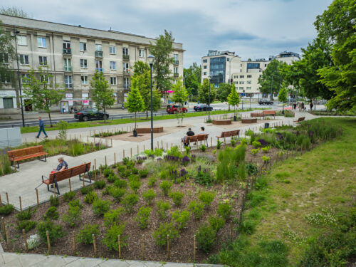 Ludzie siedzą na ławkach na skwerze Integrator