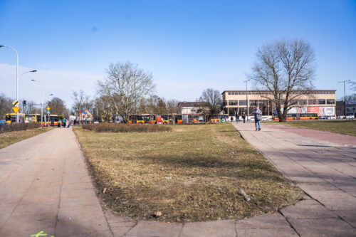 Zieleniec przy ul. Modlińskiej, chodniki, trawa, ludzie w tle, przedwiośnie