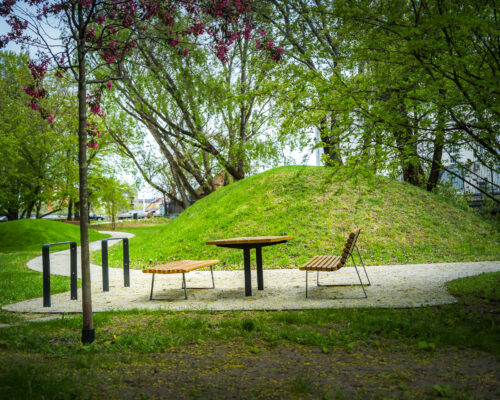Nowe ławki i stolik na skwerze, w tle zielone wzniesienie