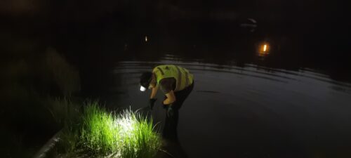 Mężczyzna z latarką patrzy w wodę