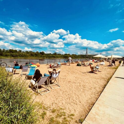 Ludzie siedzą na leżakach na plaży nad Wisłą